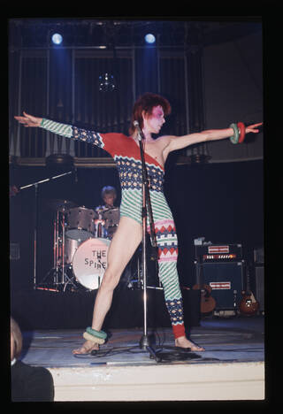 David Bowie performing as Ziggy Stardust wearing asymmetric catsuit