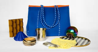A bright blue bag surrounded by shiny tactile objects including a textured brown stamper, a silver mould in the shape of a fish, a silver reflective ball and a silver beaker