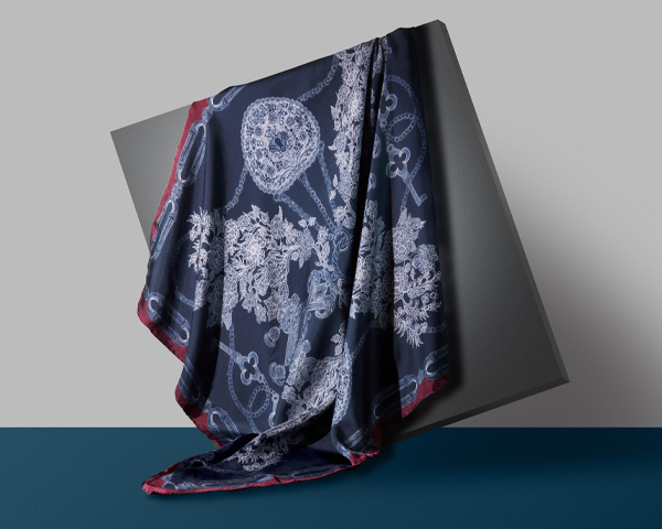 Jessie Bayliss silk scarf A navy blue scarf draped down a grey quare panel.